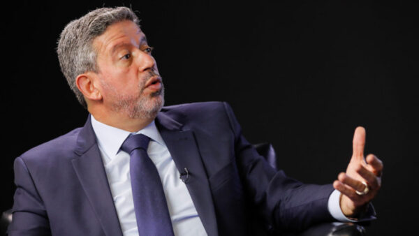 arthur lira, presidente da camara dos deputados, homem branco, com cabelos e barba grisalhos, usando roupa social escura, em um fundo escuro, com gesto assustado