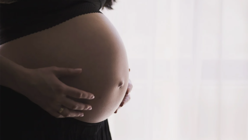 Mulher grávida com as mãos na barriga