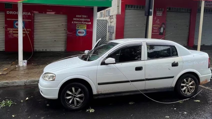 Carro parado com fio elétrico caído sobre o capô