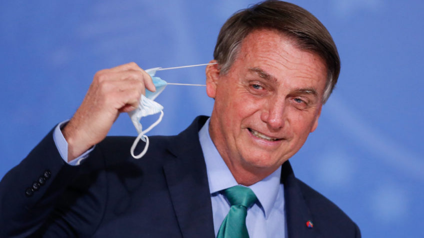 Jair Bolsonaro tirando a máscara no Palácio do Planalto